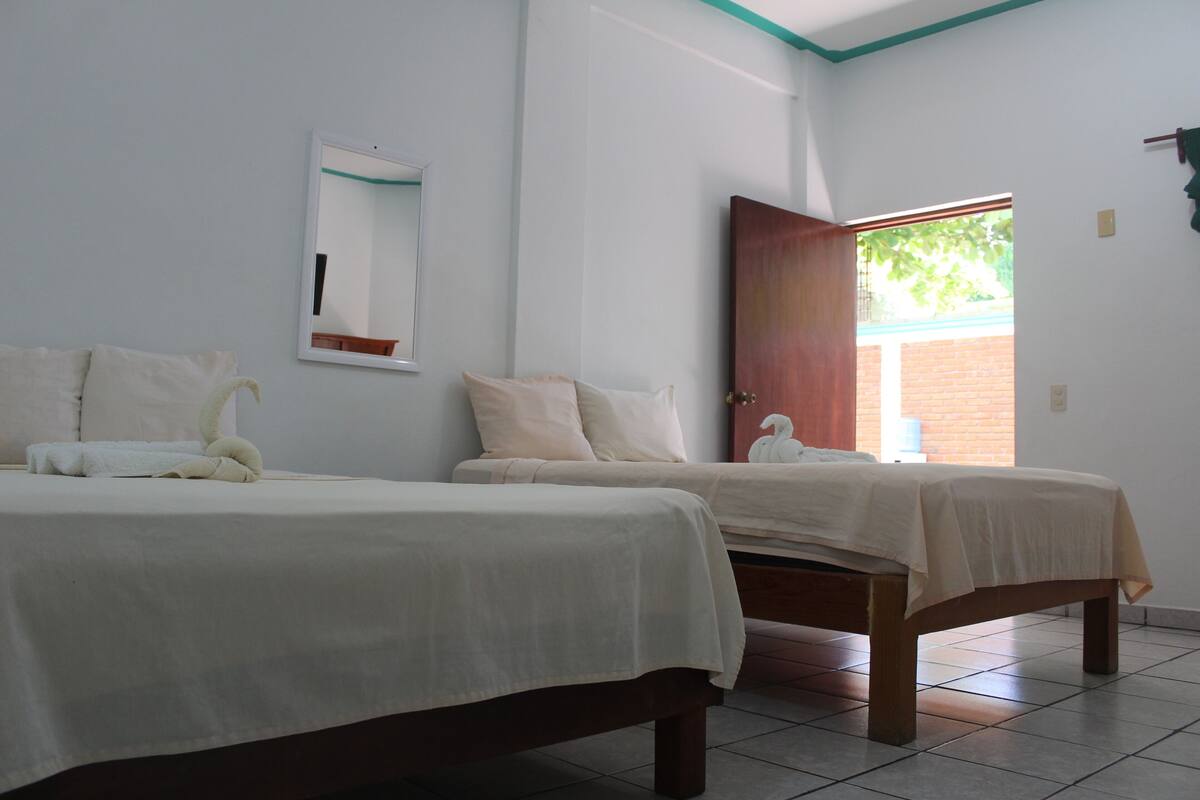 Une chambre d’hôtel avec deux lits, un miroir et une porte donnant sur un balcon.