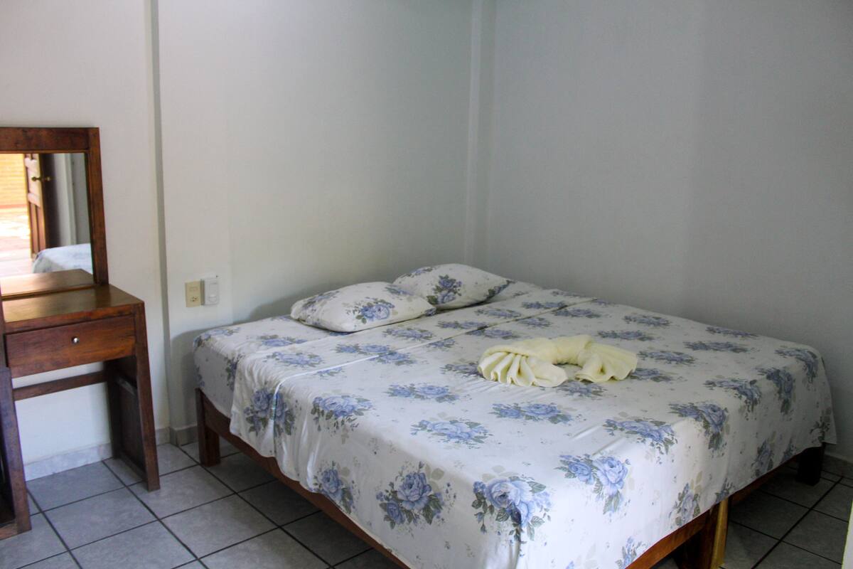 Une chambre à coucher avec un lit, une table de chevet en bois et un miroir.