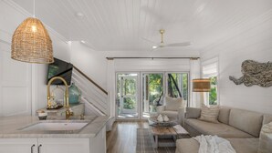 Een moderne keuken met witte kasten, een groot keukeneiland en een zithoek met een bank en tafel.