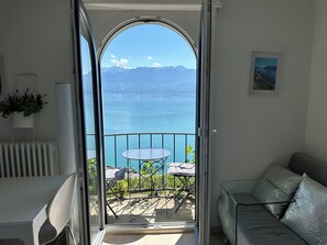 A balcony with a table and chairs, a sofa, and a view of a lake and mountains. - Stunning APT with 360 ° panoramic view of lake Geneva and Alls in the vineyard (Puidoux)