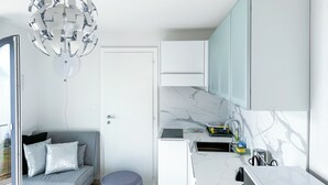 Eine moderne Küche mit Marmorarbeitsplatte, Einbauofen und Spüle. Ein graues Sofa mit Kissen und ein außergewöhnlicher Kronleuchter sind ebenfalls vorhanden.