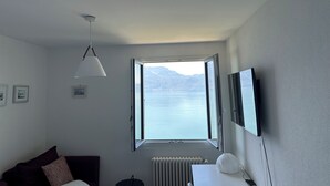 Ein Hotelzimmer mit Bett, Schreibtisch, Stuhl, Fernseher, Fenster mit Bergblick und Heizkörper.