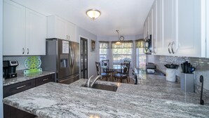 A modern kitchen with granite countertops, stainless steel appliances, and a dining area with a view. - Summer Breeze (Kissimmee)
