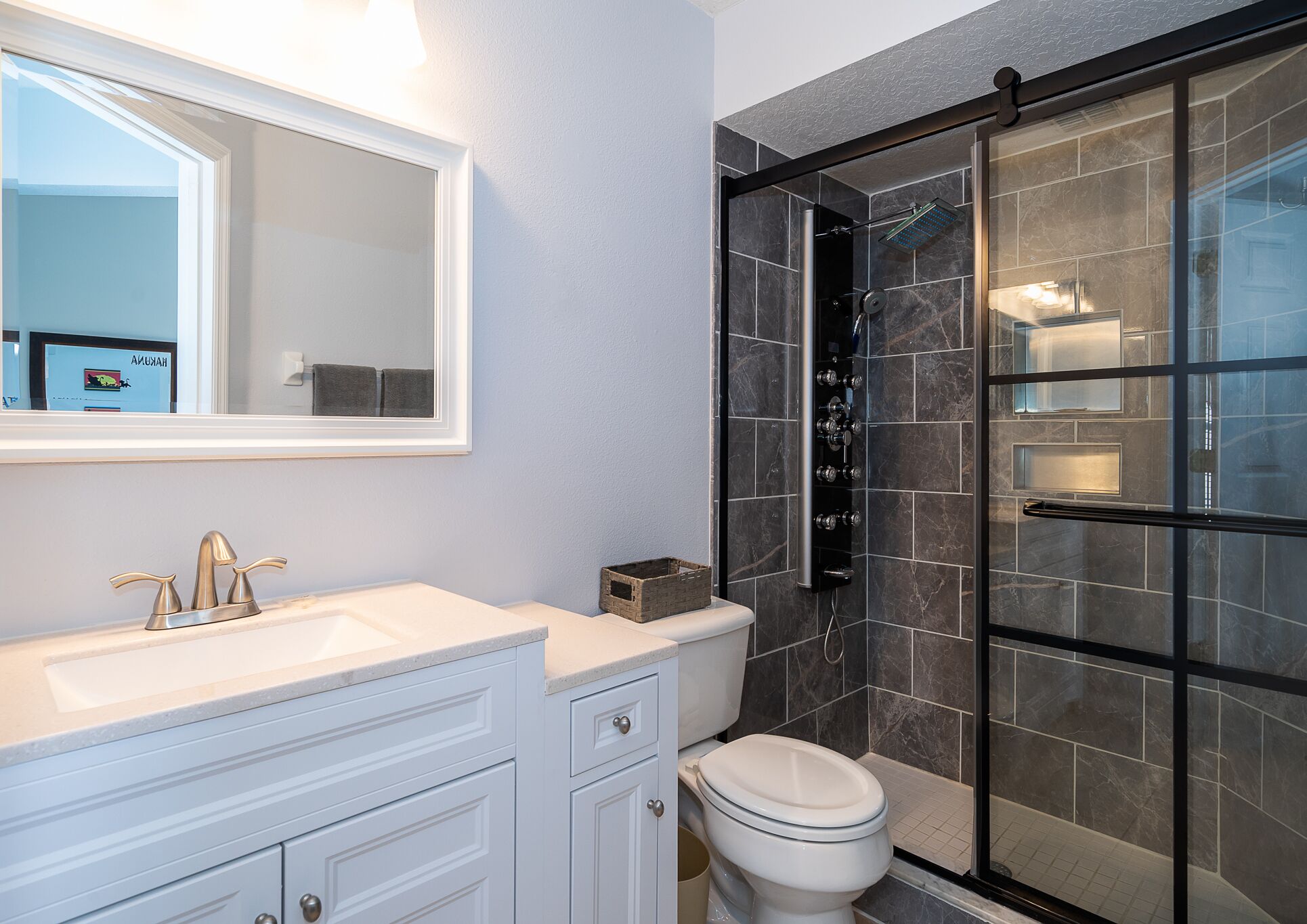 Un baño moderno con tocador blanco, inodoro y zona de ducha con mampara de vidrio.