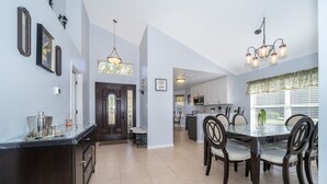 A spacious kitchen with a dining area, featuring a large island, dark cabinetry, and a chandelier. - Summer Breeze (Kissimmee)