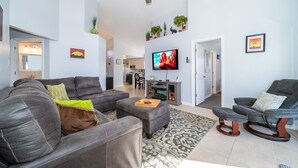 A spacious living room with a grey sectional sofa, a grey recliner, a patterned rug, and a ceiling fan. - Summer Breeze (Kissimmee)