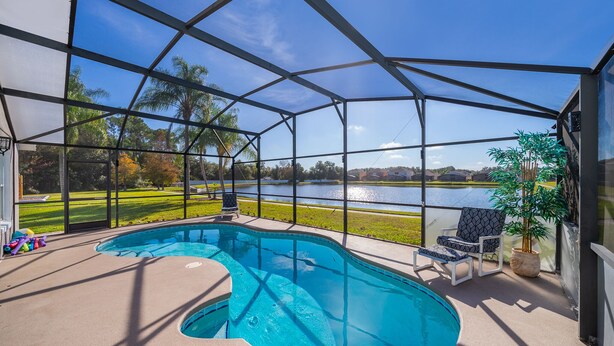 A covered outdoor swimming pool with a view of a lake and a grassy area. - Summer Breeze (Kissimmee)