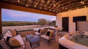 An outdoor patio with a hot tub, seating area, and a view of the landscape.