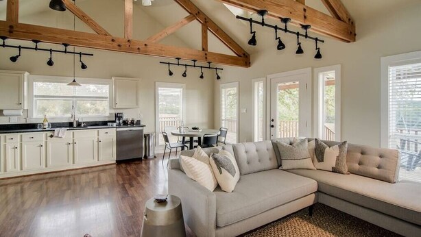 A spacious living area with a large sectional sofa, a kitchen with white cabinets, and a dining area with a table and chairs.