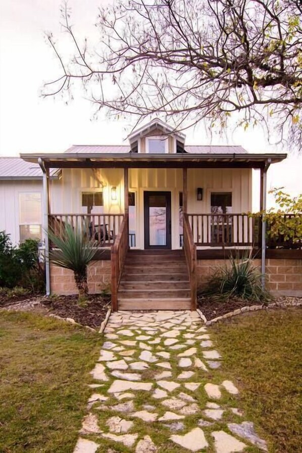 A house with a front porch, a stone pathway leading to the entrance, and a small garden with plants. - Cedar Haus: Modern Guesthouse in Fredericksburg (Fredericksburg)