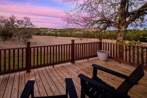 A wooden deck with a railing, a bench, and a large planter. - Cedar Haus: Modern Guesthouse in Fredericksburg (Fredericksburg)