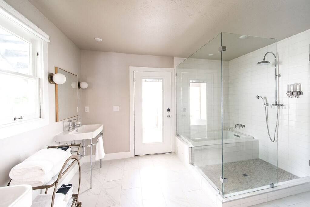 A modern bathroom with a glass-enclosed shower, a sink, and a mirror.