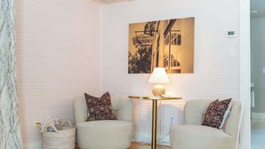 A room with two armchairs, a small table with a lamp, a wall-mounted picture, and a wicker basket. - Cozy Modern Suite in Fredericksburg (Fredericksburg)