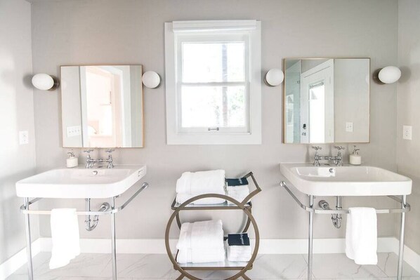 A bathroom with two sinks, a window, and a towel rack.