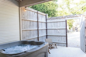 A hot tub, wooden fence, and a chair in a backyard setting.