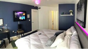 A bedroom with a bed, a TV mounted on the wall, a desk, and a chair. - Next Door To It All! Disney/Dining & More mins away 2Bed 2Bth Condo (Kissimmee)