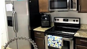 A kitchen with stainless steel appliances, wooden cabinets, and granite countertops. - Next Door To It All! Disney/Dining & More mins away 2Bed 2Bth Condo (Kissimmee)