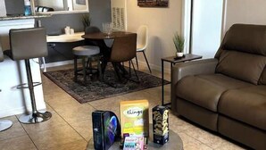 A living room with a round coffee table, a sofa, and a dining area with chairs and a table. - Next Door To It All! Disney/Dining & More mins away 2Bed 2Bth Condo (Kissimmee)