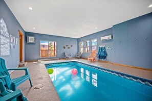 A swimming pool with a view of the outdoors, surrounded by blue walls and a wooden deck. - Luxe Pool Cabin w/MTN views! Hot Tub + Theater (Pigeon Forge)