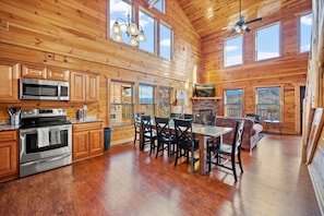 A spacious log cabin with a kitchen, dining area, and a fireplace.