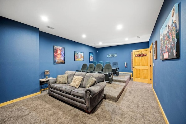 A home theater room with blue walls, a gray sofa, and multiple rows of seating.