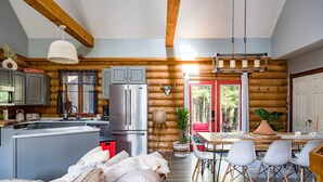 A log cabin interior with a kitchen, dining area, and a cozy living space. - Cozy Cabin Inn w/ Private Hot Tub, Fire Pit + close to Golf, Trails, Waterfalls (Owen Sound)