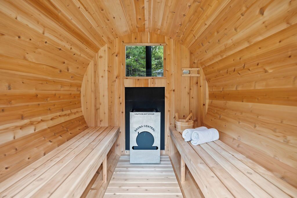 Un sauna con paredes de madera, bancos, calentador y toallas.