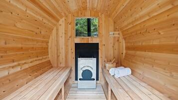 Un sauna con paredes de madera, bancos, calentador y toallas.