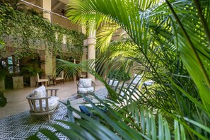 An indoor garden with seating areas, a central column, and lush greenery. - CC-2 HABITACION DOBLE EN GETSEMANI (Cartagena)