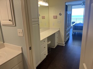 A bathroom with a white vanity, a mirror, and a towel rack. There are two signs on the wall, one saying "I'm not messy, I'm organized" and the other "I'm not messy, I'm organized."