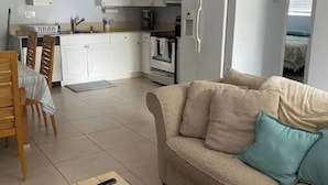 A modern apartment with a kitchenette, a dining area, and a living room with a sofa and a coffee table. - Lovely 2 Bedroom with a Pool (Jupiter)