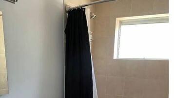 Een bad/douchecombinatie, handdoeken, toiletpapier