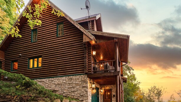 A log cabin with a stone foundation, a balcony, and a large door. - WOW! Unique Galena Dream Cabin. Hot Tub, Games, Fire Pit, Fully Stocked. (Galena)