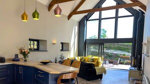 A modern kitchen with a large island, dark cabinetry, and pendant lighting. - Gloriously rural, Y Felin is a fantastic luxury barn conversion in Pembrokeshire (Ambleston)