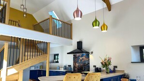 A modern kitchen with a central island, bar stools, and a staircase leading to an upper level. - Gloriously rural, Y Felin is a fantastic luxury barn conversion in Pembrokeshire (Ambleston)