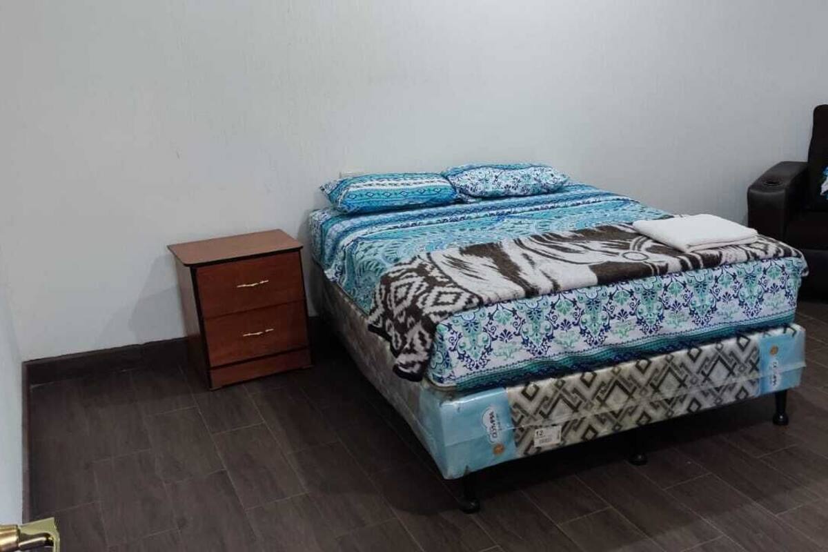 Un dormitorio con cama, mesita de noche, una silla y un armario.