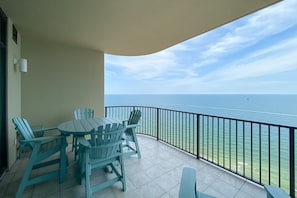 Un balcon avec vue sur l’océan, une table avec des chaises et une rambarde.