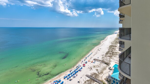 A beachfront hotel with a balcony overlooking the ocean, beach umbrellas, and a clear view of the sea. - Phoenix West 2207 Upscale Luxury | Updated | Beachfront | Waterslide-Lazy River (Orange Beach)