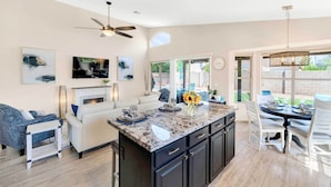 A modern kitchen with a central island, dark cabinetry, and a dining area with a round table and chairs. - Close to Spring Training! Serene Retreat in Gibert (Gilbert)