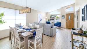 A modern living room with a grey sectional sofa, a dining table set for four, and a hanging light fixture. - Close to Spring Training! Serene Retreat in Gibert (Gilbert)