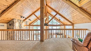 Spazioso loft con soffitto alto, travi in legno a vista, parete in pietra e vista sull'esterno.