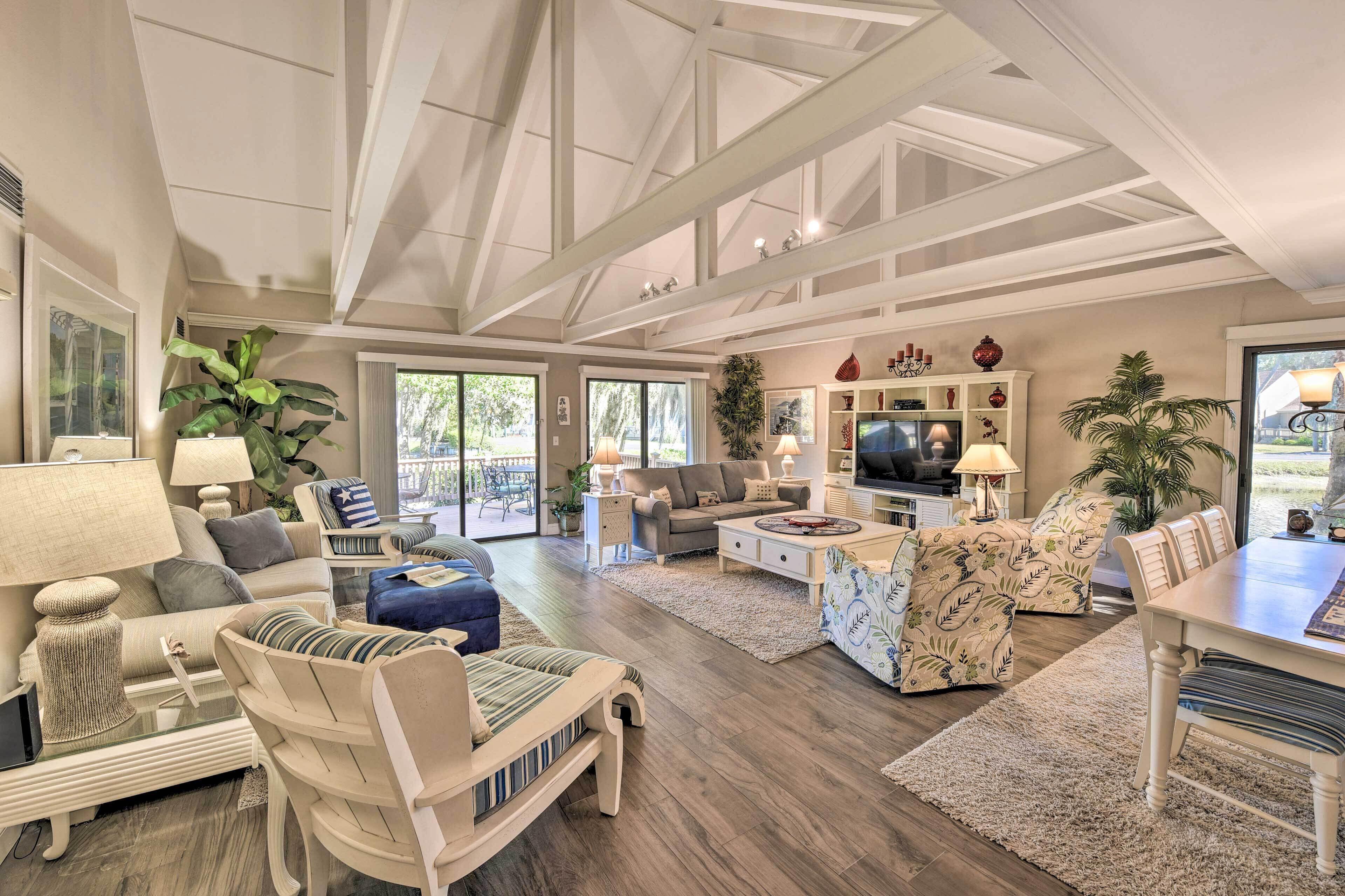 A spacious living room with a high ceiling, a television, and a dining area with a table and chairs.