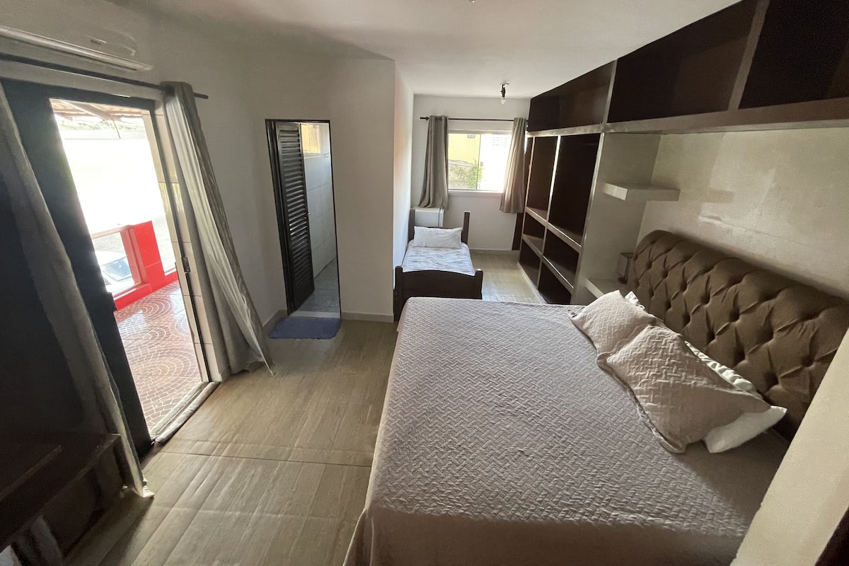 A hotel room with a bed, a wardrobe, a mirror, and a sliding door leading to an outdoor area.