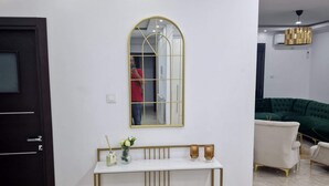 Un salon moderne avec une console blanche, un grand miroir et un canapé vert.