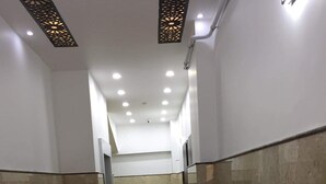 Un couloir doté d’un sol en marbre, de murs blancs et d’un panneau décoratif au plafond.