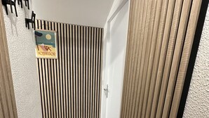 Un couloir étroit aux murs recouverts de lambris en bois, une porte au fond et un tableau encadré accroché au mur.