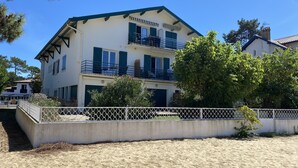 Un immeuble de deux étages doté de balcons, d’une façade blanche et entouré d’une clôture blanche.