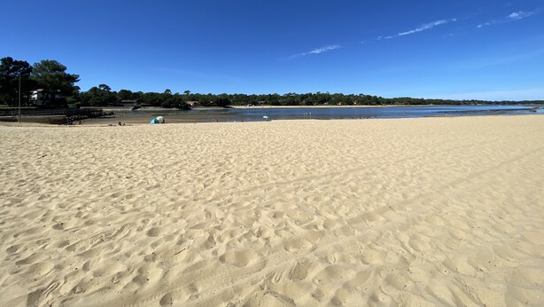 Une vaste plage de sable fin, sous un ciel bleu et dégagé.
