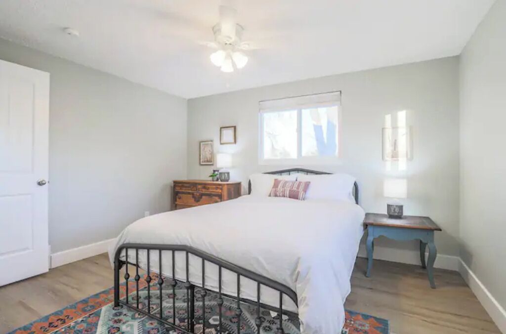 A bedroom with a bed, a nightstand, a dresser, and a window.