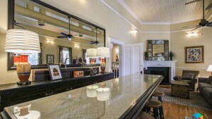 A spacious living area with a large glass-top bar, a fireplace, and a ceiling fan.